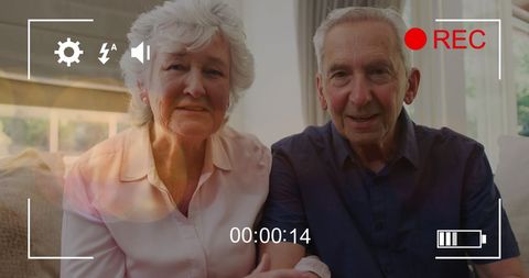 Senior couple smiling at home with recording overlay
