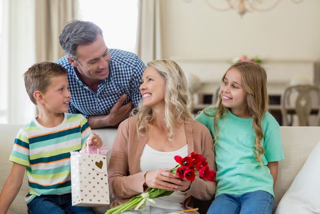Parents and kids interacting on sofa with present in living room at home
