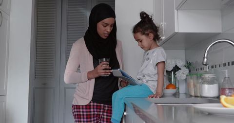 Mother and Daughter Enjoy Digital Tablet Time in Modern Kitchen