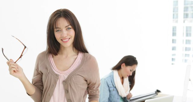 Smiling Businesswoman Holding Glasses in Bright Office Environment - Download Free Stock Images Pikwizard.com