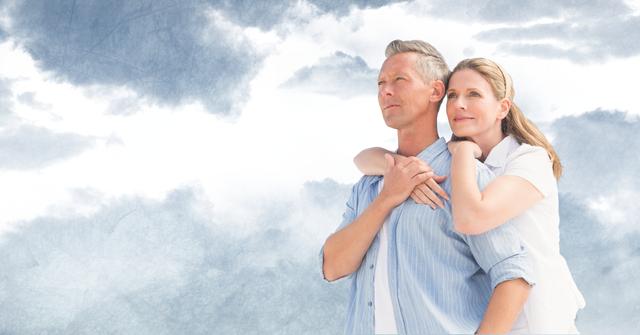 Mature couple standing closely together, embraced under a partly cloudy sky. Their expressions convey a deep emotional bond, tranquility, and contentment. This image can be used for themes of romance, partnership, togetherness, or promotional material for lifestyle and relationship content.