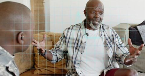 Senior man sharing story on living room sofa gesturing during warm family conversation