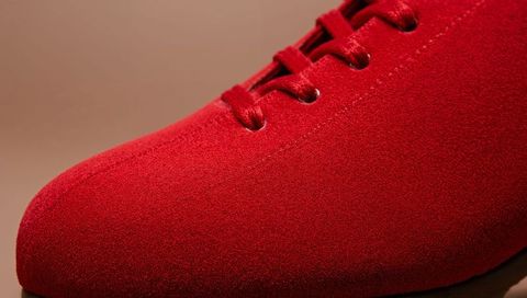 Crimson suede dress shoe closeup showing satin laces, precise stitching and velvet nap