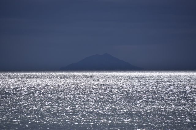 Glistening Ocean Under Dusk Sky with Mountain Silhouette - Download Free Stock Photos Pikwizard.com