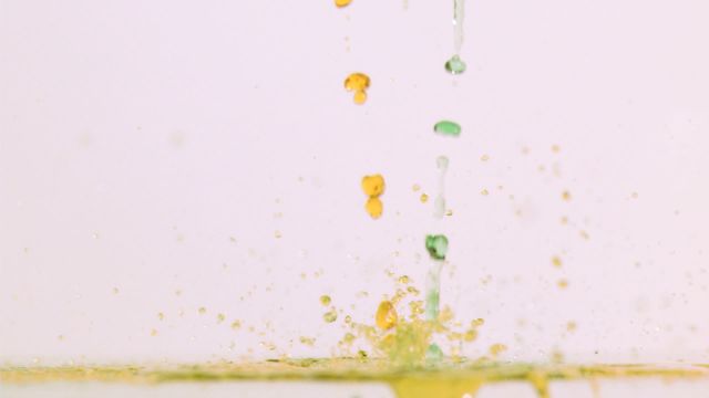 Abstract bright colored liquids dripping in super slow motion against white background. Highlights detail and vivid colors, making it perfect for science demonstrations, art projects, and educational materials related to fluid dynamics or chemistry.