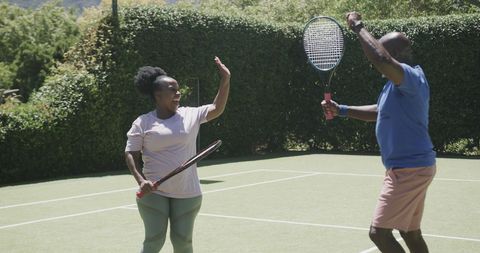 Cheerful Senior African American Couple Playing Tennis