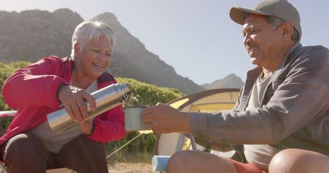 Joyful Senior Couple Camping and Pouring Tea Outdoors