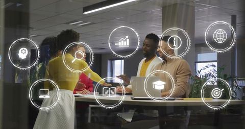 Diverse team collaborating around high table with laptop and floating business tech icons