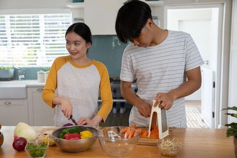 Asian couple cooking together in contemporary kitchen setting