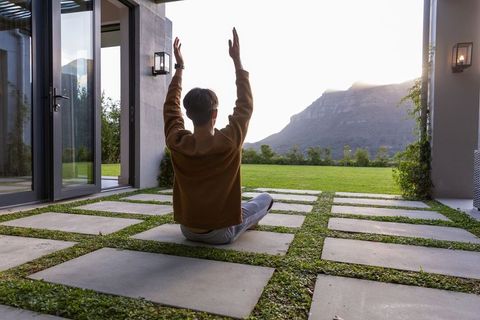 Man practicing meditation on modern patio with mountain view at sunrise and square pavers