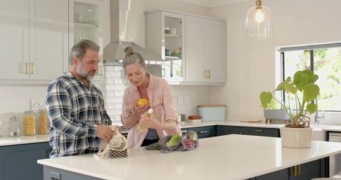 Mature Couple Unpacking Groceries in Modern Kitchen