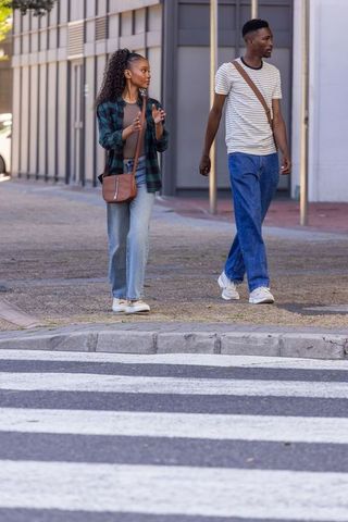 African couple walking and talking across zebra crossing in casual urban fashion