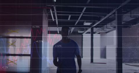 Silhouetted man standing in industrial warehouse wearing shirt with data chart overlay