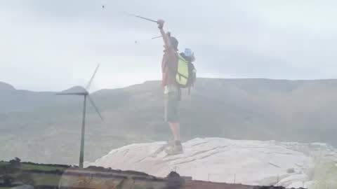 Hiker Conquering Summit Integrating Eco-Friendly Technology