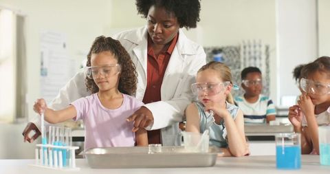 African american teacher guiding elementary students in hands-on chemistry lab experiment