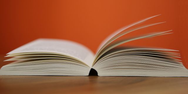 Open Book on Wooden Table Against Orange Background - Download Free Stock Photos Pikwizard.com