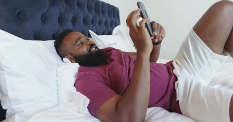 Man Relaxing on Bed Enjoying Smartphone in Modern Bedroom