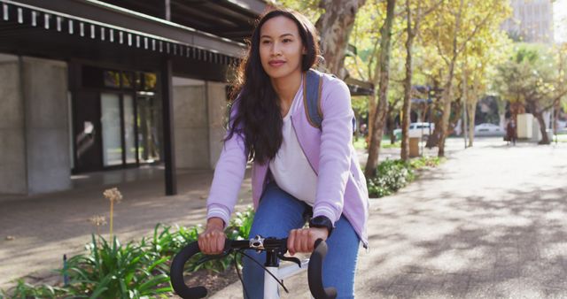 Asian woman wearing backpack smiling while riding bicycle on the road. modern lifestyle and living concept