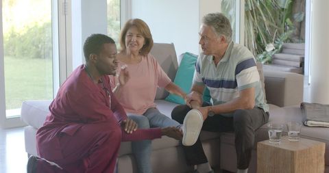 Healthcare professional assisting senior couple at home for elderly care