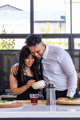 African american couple cooking together, laughing and leaning at kitchen island