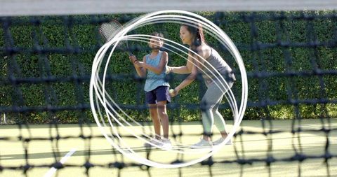 Female coach guiding young girl tennis grip on outdoor court mentoring youth sports and family fitne