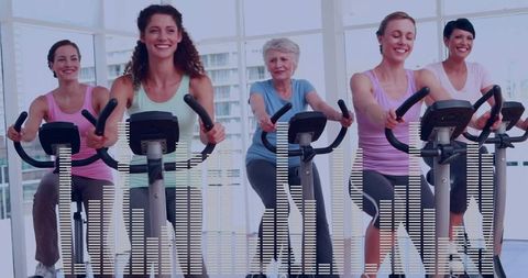 Group of Women Exercising on Indoor Cycling Machines in Fitness Studio