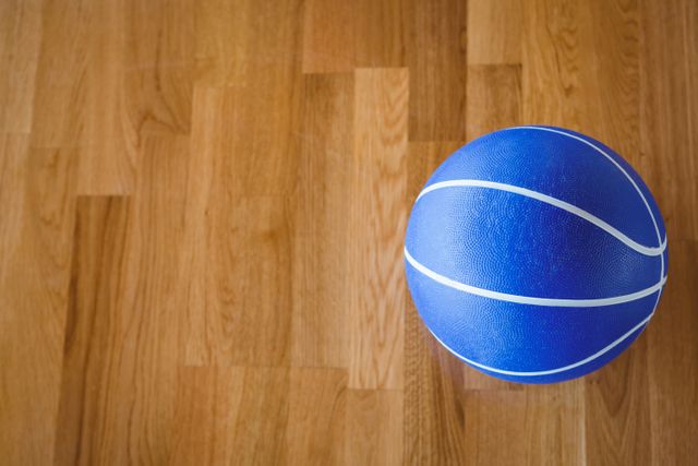 Overhead view of blue basketball on hardwood floor in court