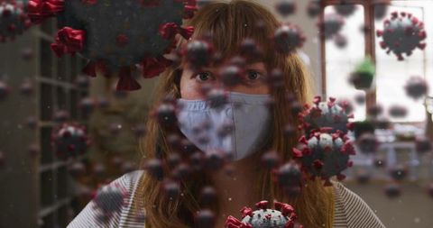 Woman wearing cloth mask in home office surrounded by coronavirus particle overlay