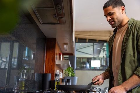 Man Cooking in Modern Kitchen Pouring Olive Oil into Pan