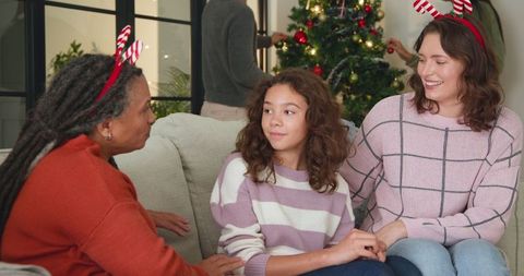 Diverse family celebrating christmas sitting together on sofa