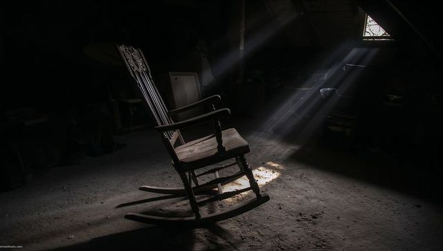 Vintage wooden rocking chair with sunbeams in dusty workshop