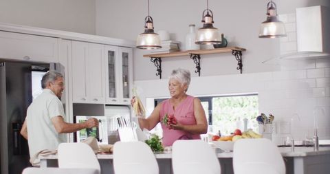 Senior Couple Organizing Groceries in Modern Kitchen