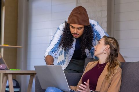 Two colleagues collaborating over laptop in modern lounge for teamwork and productivity