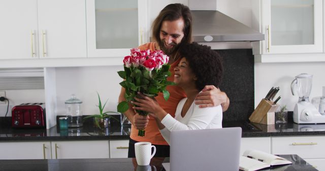 Caucasian man giving a flower bouquet to his wife in the kitchen at home. staying at home in self isolation in quarantine lockdown