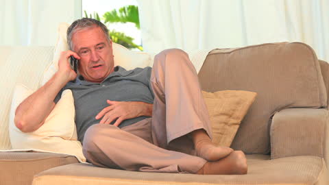 Middle Aged Man Relaxing and Chatting on Phone at Home