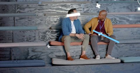 Colleagues chatting on tiered bench with lanyards, cushions and woodgrain