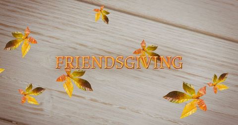 Friendsgiving Text with Autumn Leaves on Wooden Background
