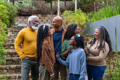 African american multigenerational family gathering on garden steps, laughing and embracing