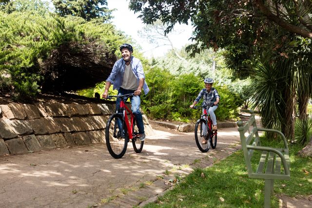 Couple enjoying a bike ride in a lush park on a sunny day. Ideal for promoting outdoor activities, healthy lifestyles, and leisure time. Perfect for use in advertisements, brochures, and websites related to fitness, recreation, and nature.