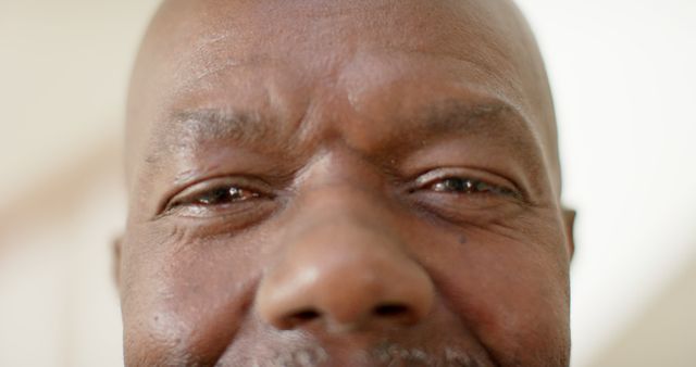Portrait close up of eyes of happy senior african american man smiling at home. Retirement, wellbeing, domestic life, and senior lifestyle, unaltered.