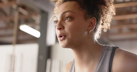 Female athlete pausing to breathe after intense cardio set in industrial gym