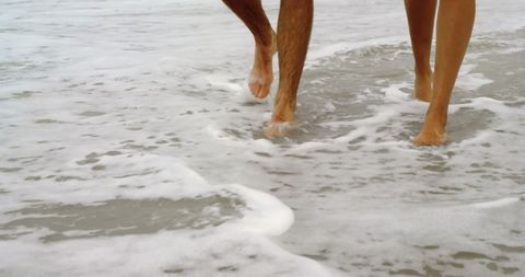 Couple Walking Barefoot on Beach Shoreline