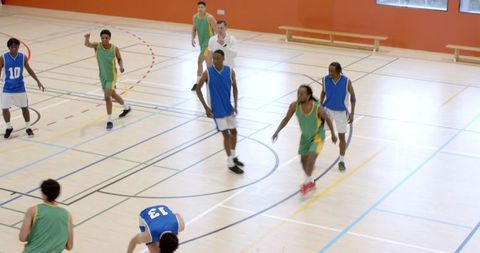 Diverse basketball players sprinting on indoor court