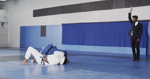 Grappling Match with Referee Signaling in Martial Arts Gym