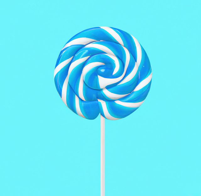 Close up of round blue and white lollipop on blue background. Candy, sweets, food and drink concept.