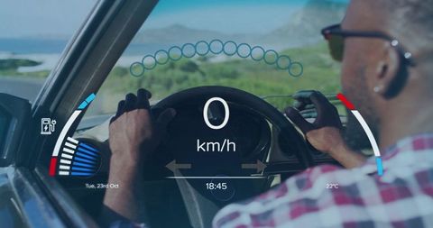 Driver holding steering wheel checking hud display while driving along coastal road