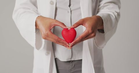 Doctor Standing with Red Heart in Hands Symbolizing Health Care