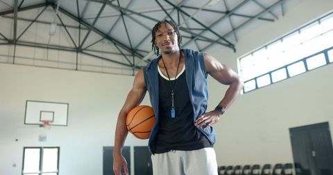 Athletic coach holding basketball on indoor court confidently