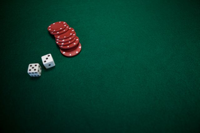This image shows a pair of dice and a stack of red casino chips on a green poker table. It is ideal for use in articles or advertisements related to gambling, casinos, poker games, and entertainment. It can also be used for promoting casino nights, gaming events, or illustrating concepts of luck and chance.