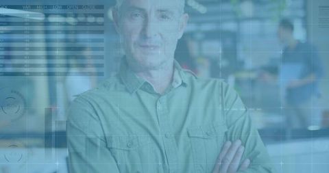 Mature supervisor standing with arms crossed in industrial workshop with digital hud